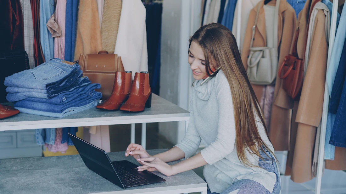 Lojista usando o notebook no balcão da loja de roupas